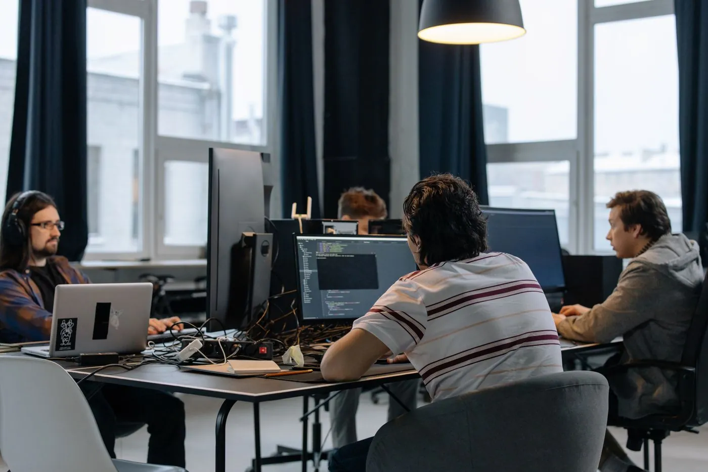 Entwickler an mehreren Arbeitsplätzen, Symbolbild für technische Zusammenarbeit